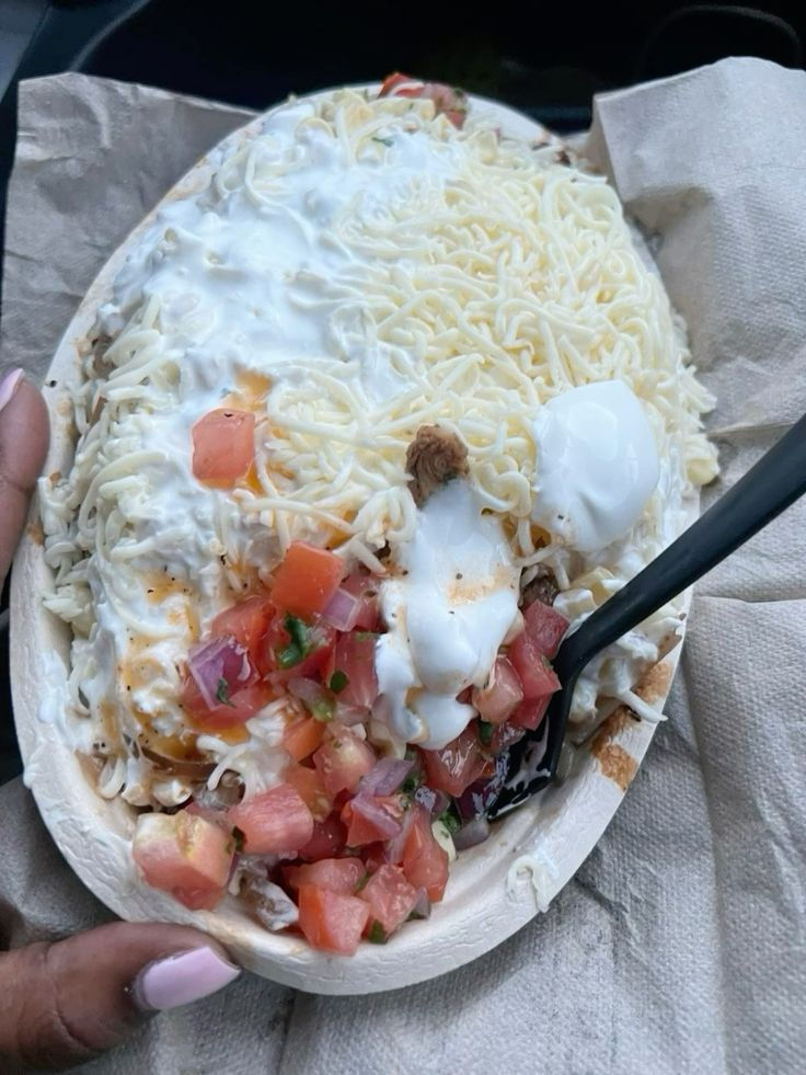 a person is holding a plate of food with cheese, tomatoes and other toppings