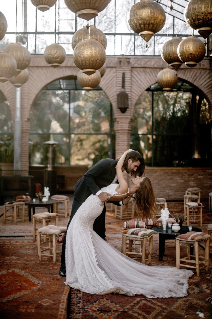 a bride and groom are kissing in an elegant setting with chandeliers hanging from the ceiling