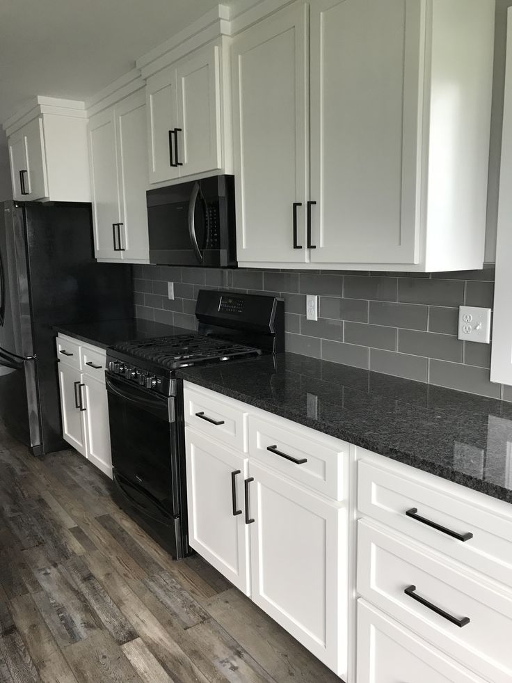 a kitchen with white cabinets and black appliances