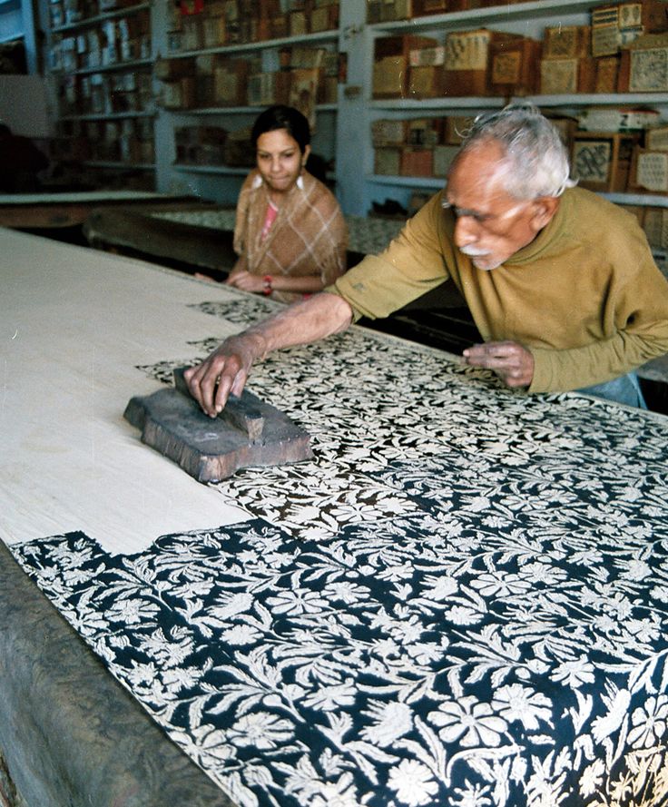 an old man and woman are working in a shop