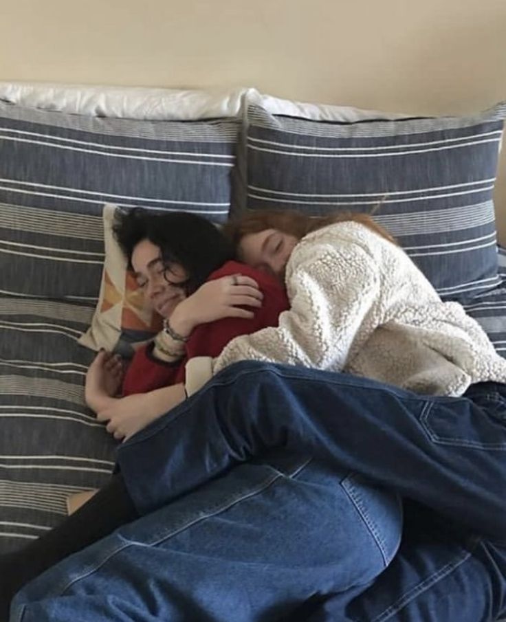 a man and woman laying on top of a bed next to each other with their arms around each other