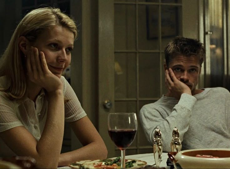 a man sitting next to a woman at a table in front of a plate of food