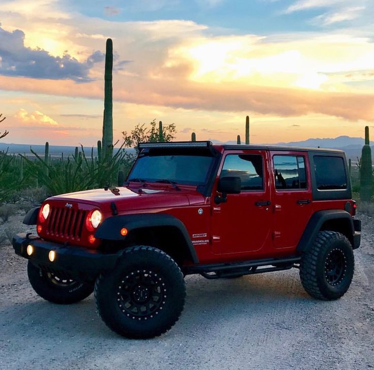 a red jeep is parked in the desert