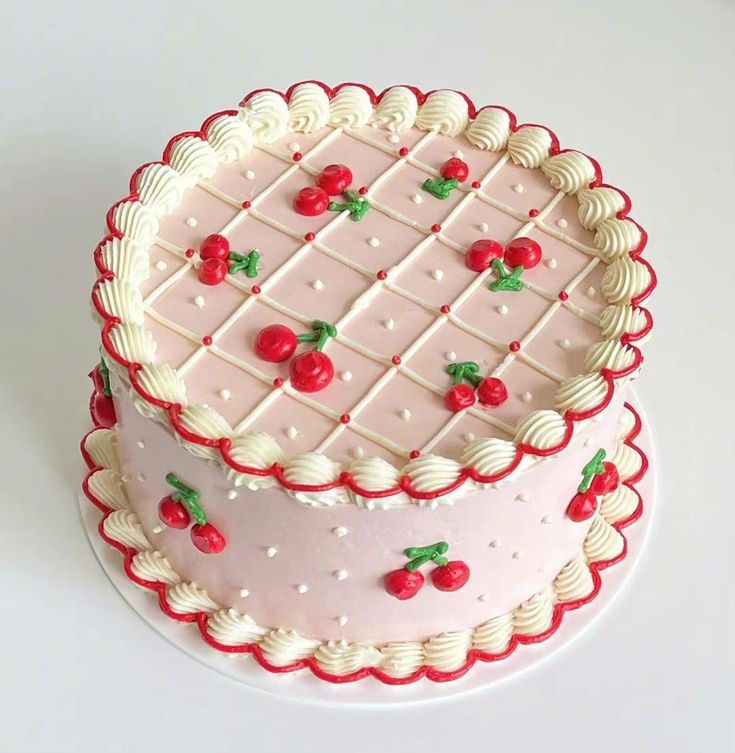 a pink cake with cherries on it sitting on a white table next to a fork and knife