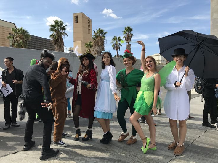 a group of people standing around each other holding umbrellas and posing for the camera