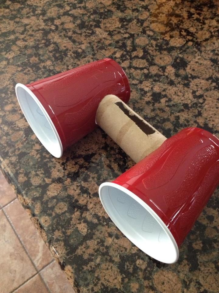 two red cups sitting on top of a counter next to a roll of toilet paper