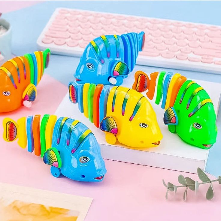 four colorful plastic fish sitting on top of a table next to a keyboard and mouse