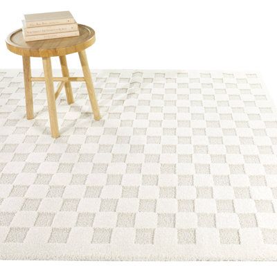 a table with a book on top of it in front of a white wall and checkered rug