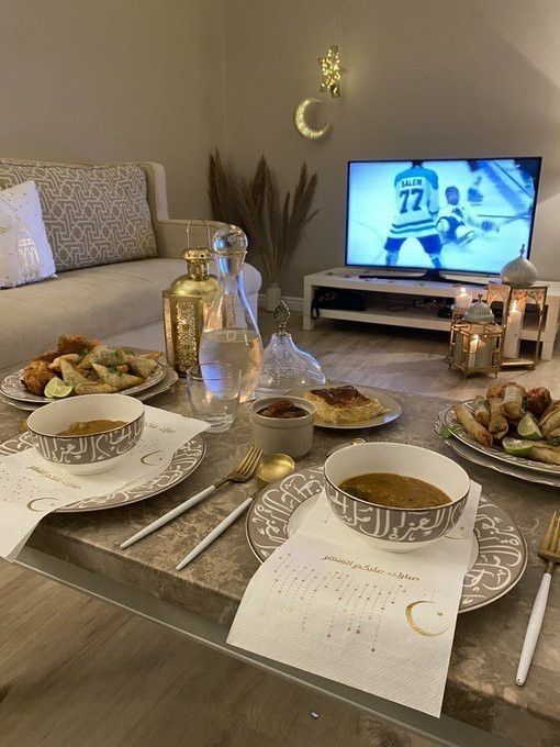 a table with plates and bowls of food on it in front of a flat screen tv