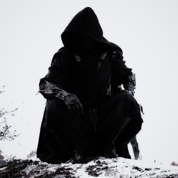 a person sitting on top of a snow covered hill wearing a black hooded jacket and holding a knife