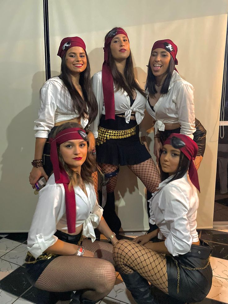 four women dressed up in pirate costumes posing for a photo together, with one woman sitting on the floor