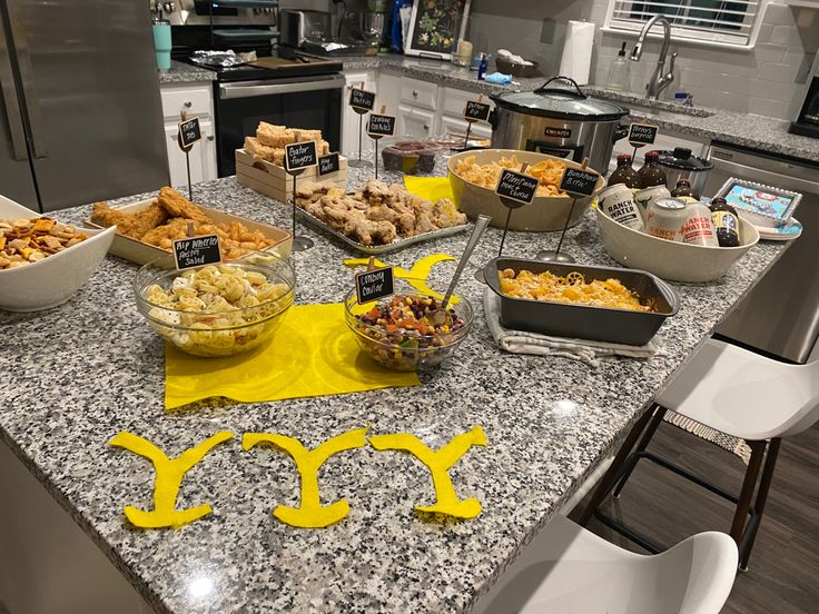 a kitchen counter topped with lots of different types of foods and desserts on top of it