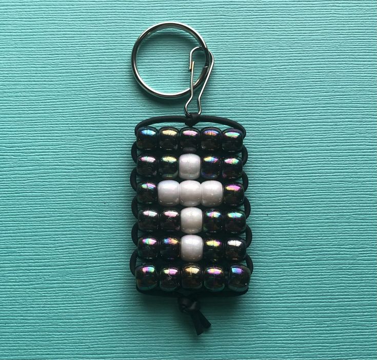 a keychain made out of beads on top of a blue surface with a black cord