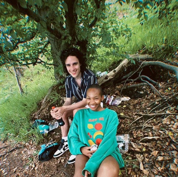 two people sitting on the ground in front of a tree