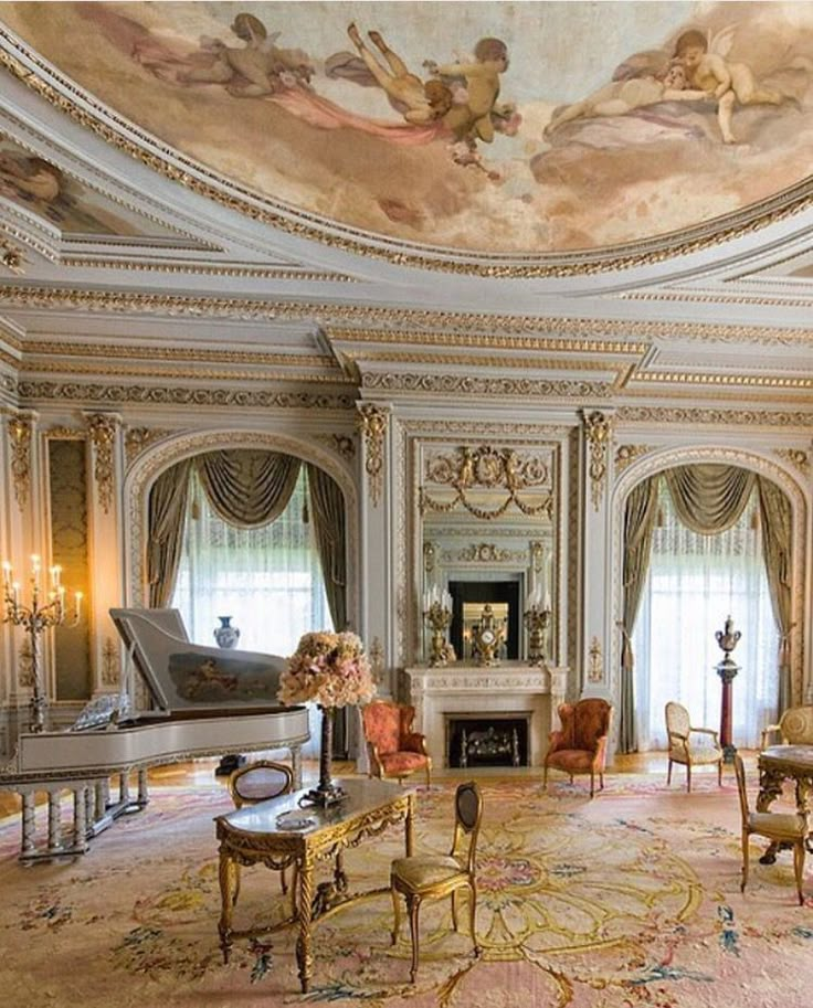 an ornate living room with chandeliers and paintings on the ceiling, painted in gold