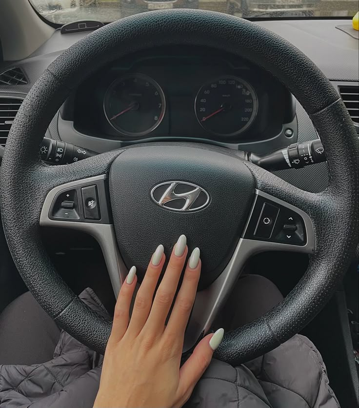 a woman driving a car with her hands on the steering wheel