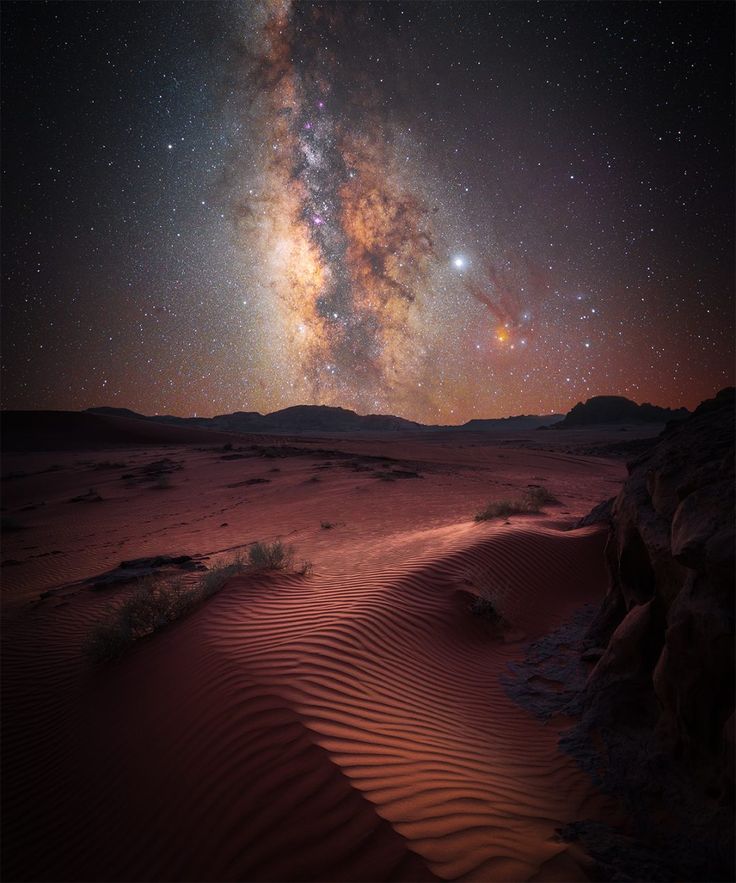 the night sky is filled with stars and bright lights as it shines over sand dunes