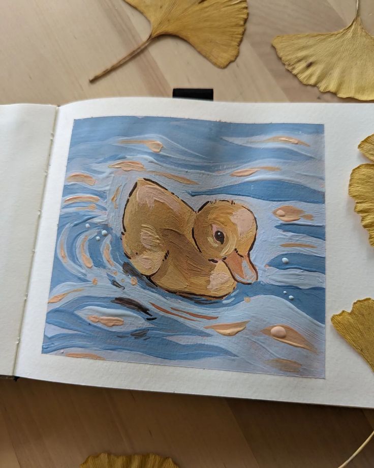 an open book with some leaves surrounding it and a duck in the water on top