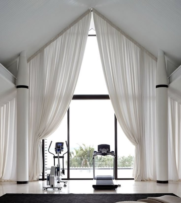 a room with white curtains and black rugs on the floor next to a large window