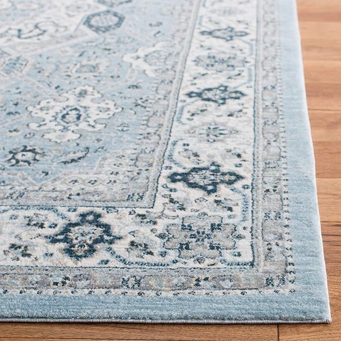 a light blue rug with an ornate design on the top and bottom, laying on a wooden floor