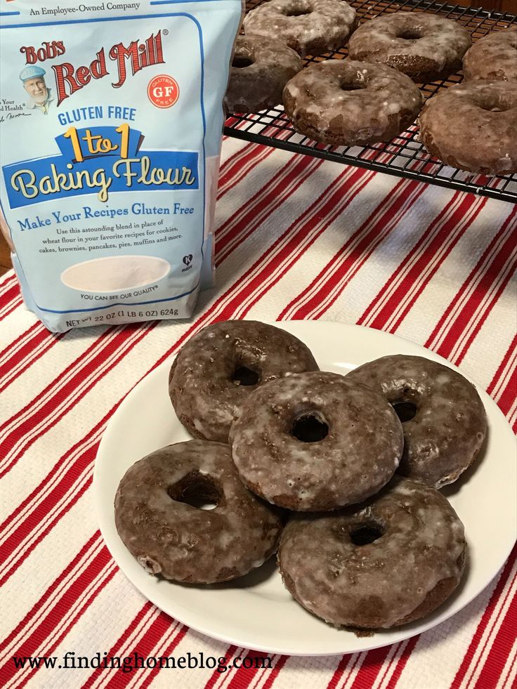 chocolate donuts are on a plate next to a bag of flour