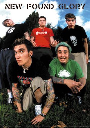 a group of young men sitting next to each other on top of a grass covered field