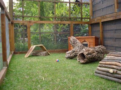 an outdoor play area with wood logs and other items in the grass near a fence