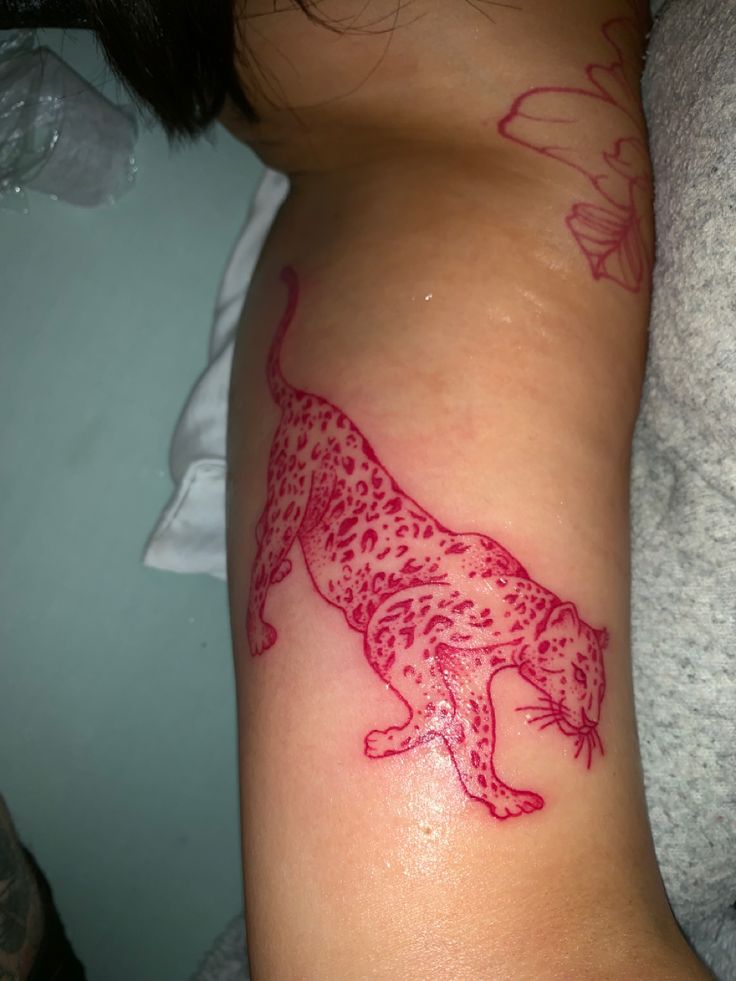 a woman with a tattoo on her arm that has a red leopard design on it