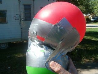 a person wearing a red and green helmet on their head with a plastic bag over his face