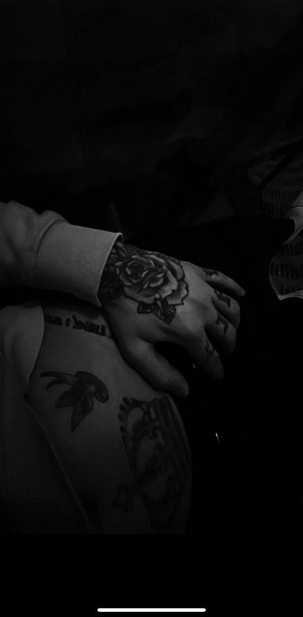 a person with tattoos on their arm and hand next to a remote control in the dark