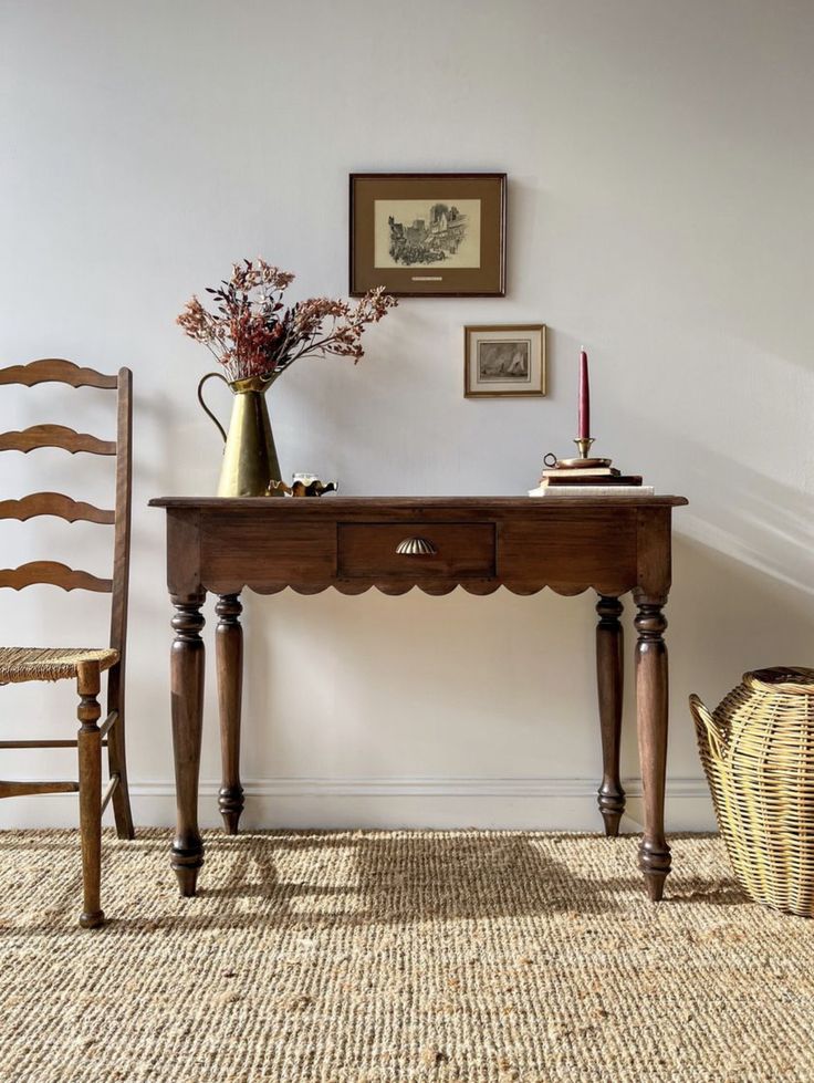 a wooden table with two chairs next to it and a vase filled with flowers on top