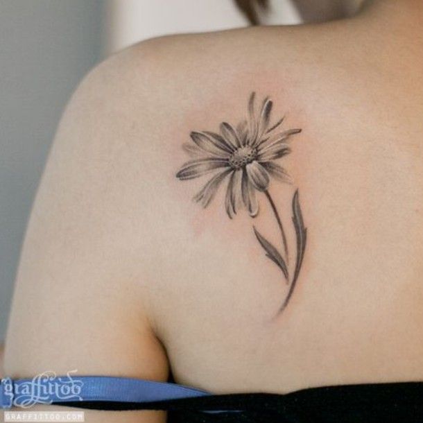 the back of a woman's shoulder with a flower tattoo on it