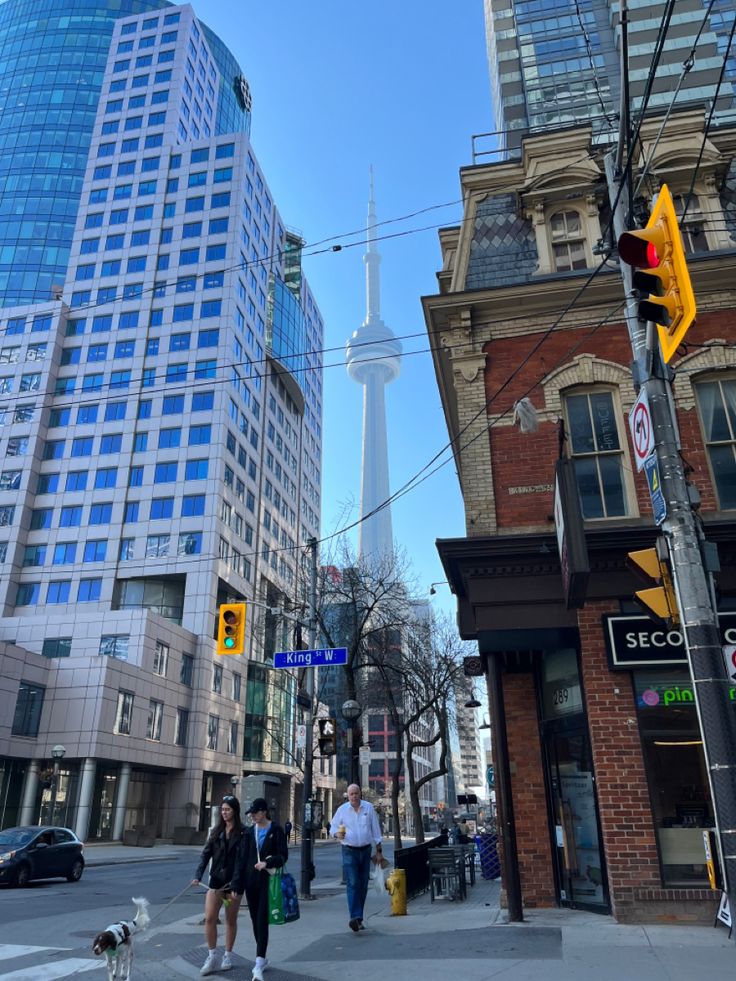 people are walking down the street in front of some tall buildings and a yellow traffic light