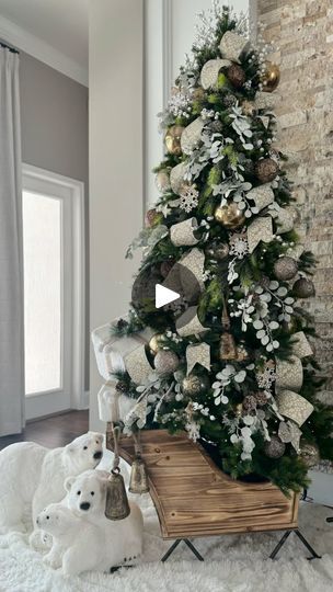 a decorated christmas tree with white and gold ornaments in a living room next to a brick wall