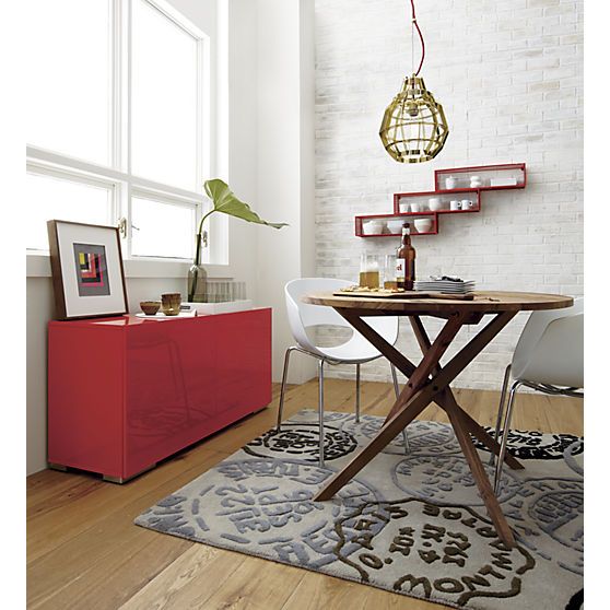 a dining room table with chairs and a shelf on the wall in front of it