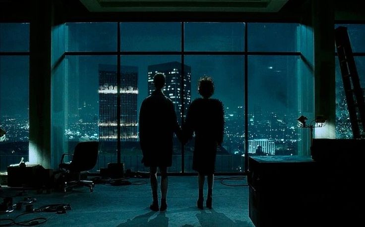 two people standing in an office looking out the window at cityscape and skyscrapers