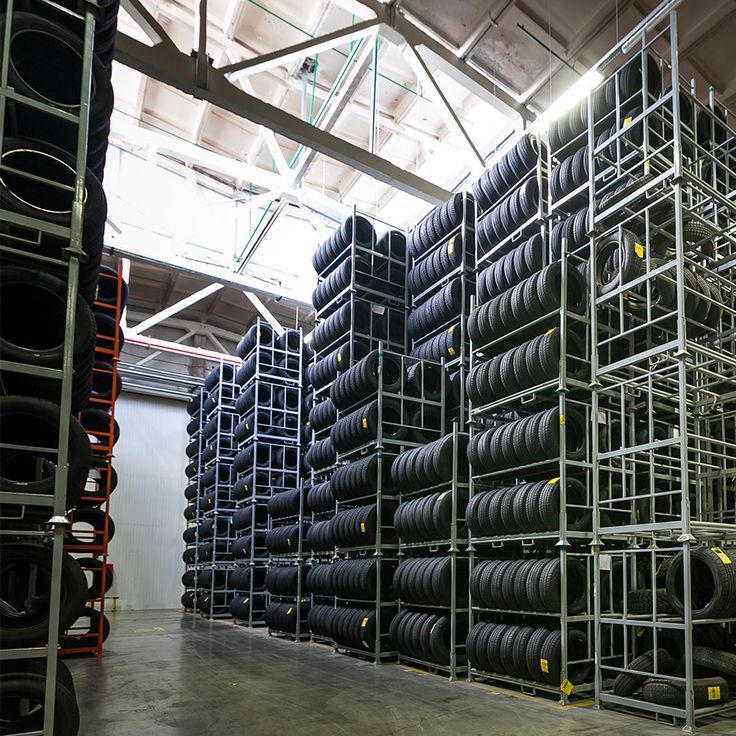 stacks of tires are stacked up in a large room with metal racks on the wall