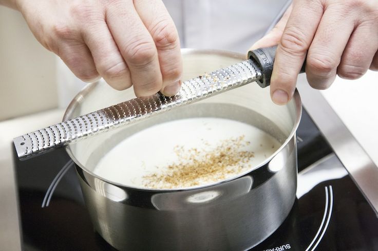 a person using a grater to stir food in a pot on top of the stove