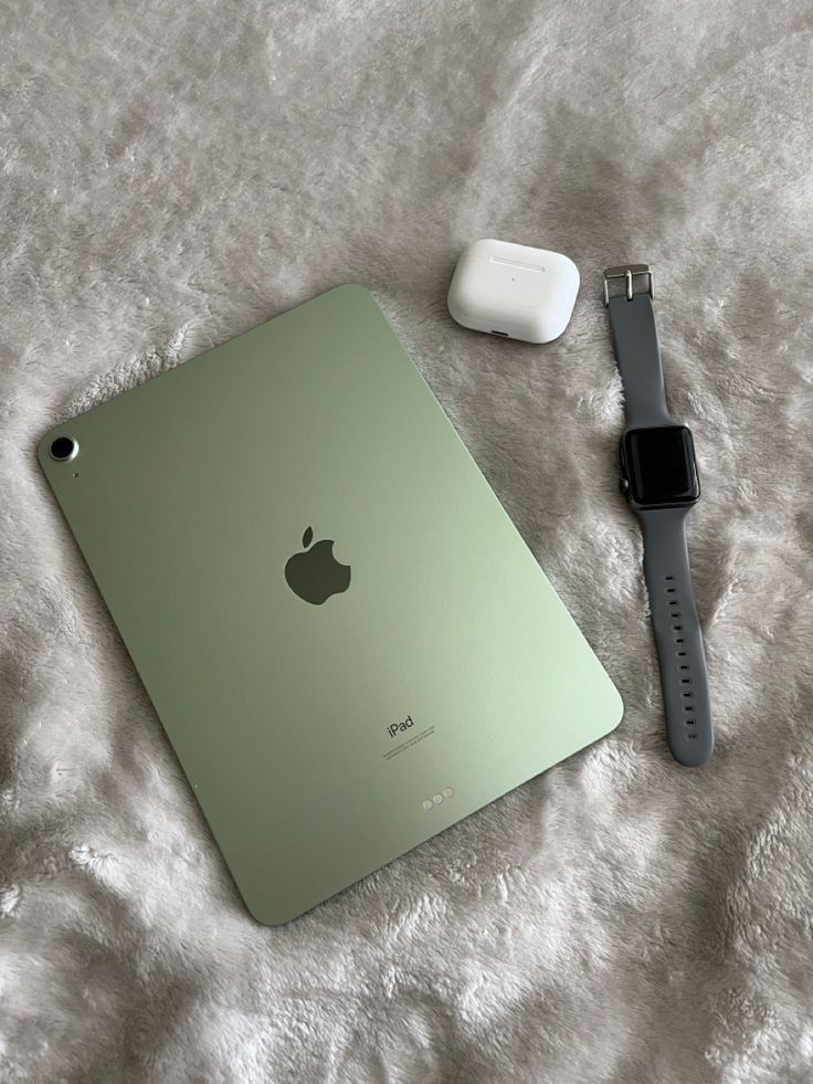 an apple laptop and headphones on a bed