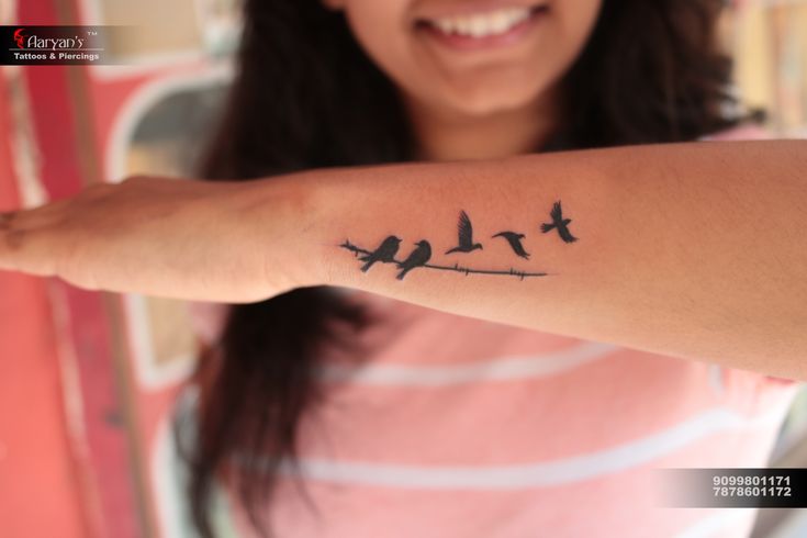 a woman with a tattoo on her arm that has birds on it and is smiling at the camera