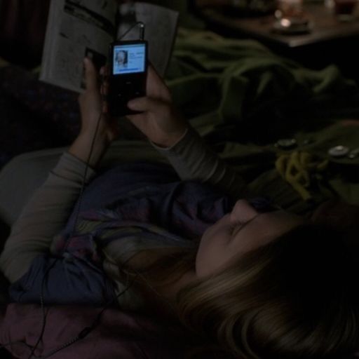 a woman laying in bed reading a book and holding up her cell phone to take a photo