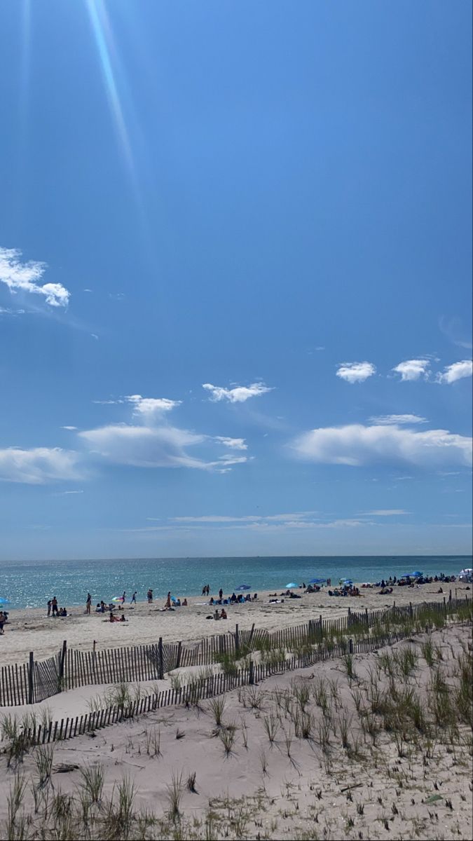 the beach is crowded with people and umbrellas on a sunny day in front of the ocean