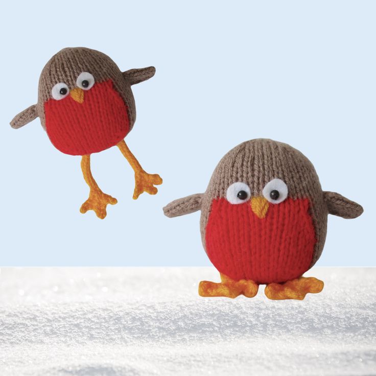 two knitted birds sitting on top of snow covered ground