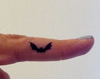 a person's finger with a bat tattoo on it