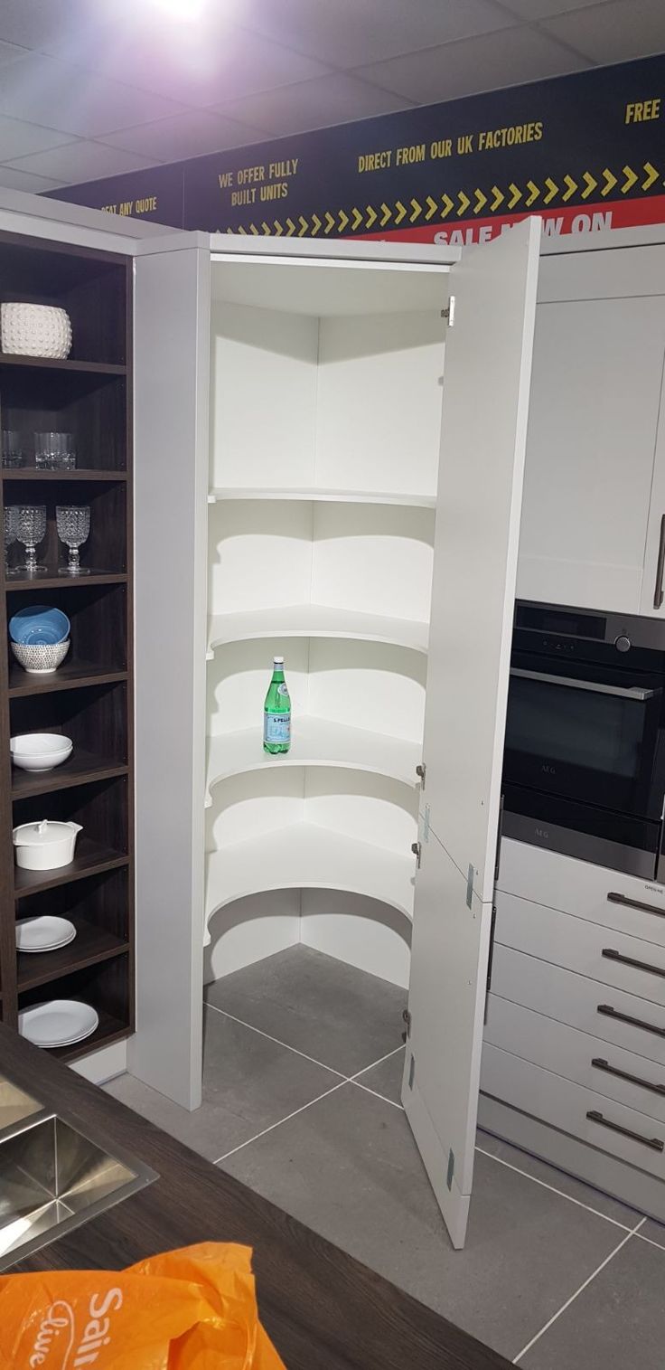 a kitchen with white cabinets and shelves filled with dishes