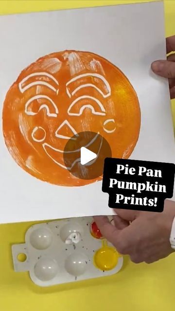 a person is painting an orange pumpkin with white paint on the paper and then it's cut out