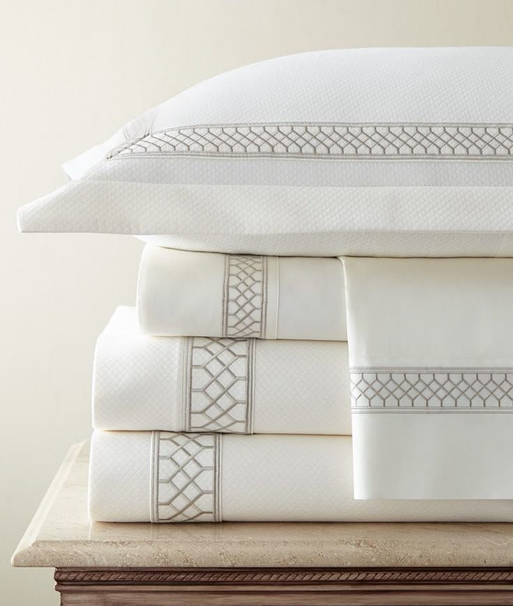 a stack of white sheets and pillows on top of a table