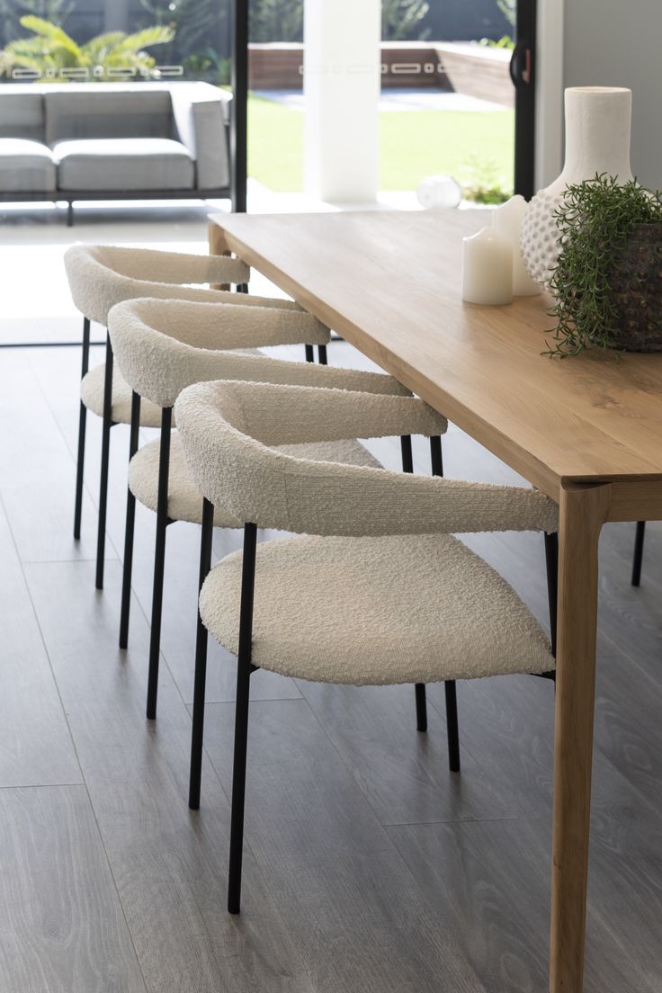 a wooden table topped with lots of white chairs