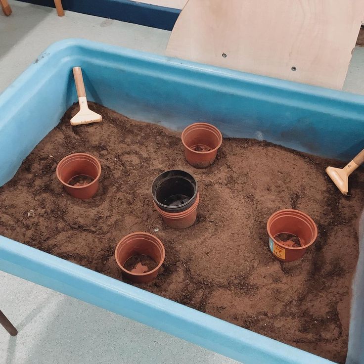 children's sand and water play area with shovels, pots and cups in it