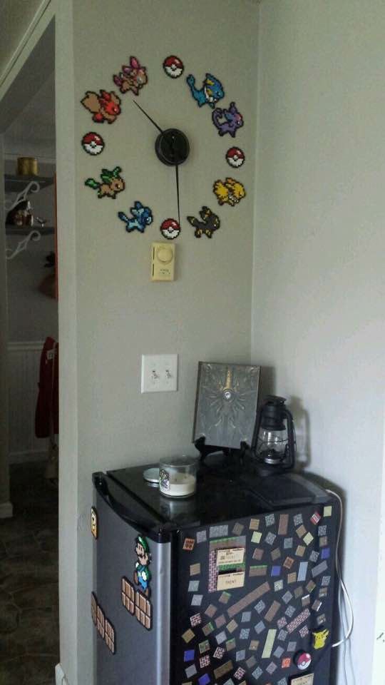 a clock on the wall above a trash can in a room with white walls and flooring